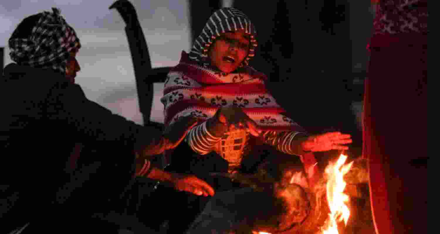 People warm themselves around a bonfire on a foggy winter morning, in New Delhi, Saturday. 