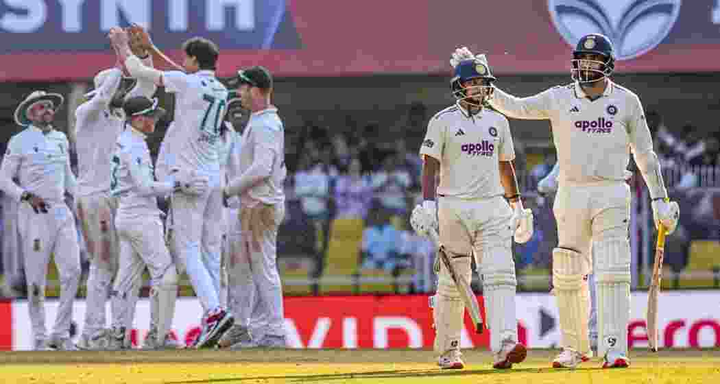 India's Kuldeep Yadav and Jasprit Bumrah walk off the ground as South Africa's players gesture on the third day of the third Test cricket match between India and South Africa at the Barsapara Cricket Stadium in Guwahati on Monday.