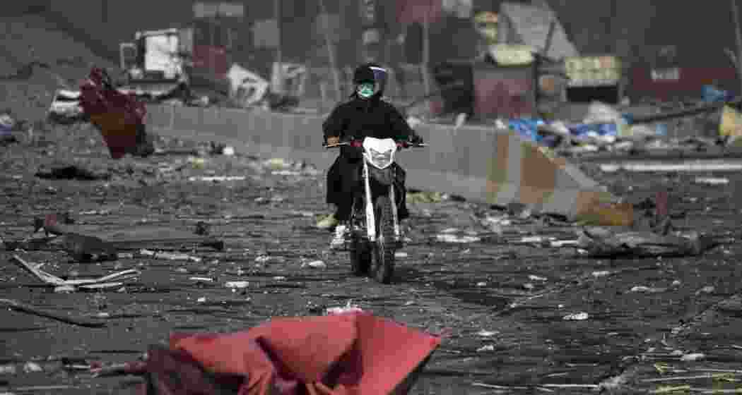 Men ride a motorcycle amid the devastation on a boulevard following an explosion at the Shahid Rajaee port dock southwest of Bandar Abbas in the Iranian province of Hormozgan on April 26, 2025.