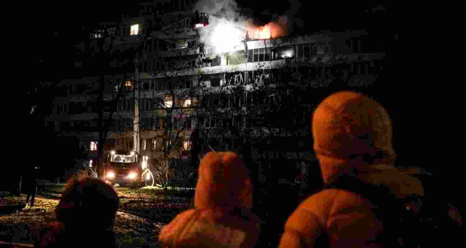 People looking at a damaged apartment building after a Russian attack in Kyiv, Ukraine.