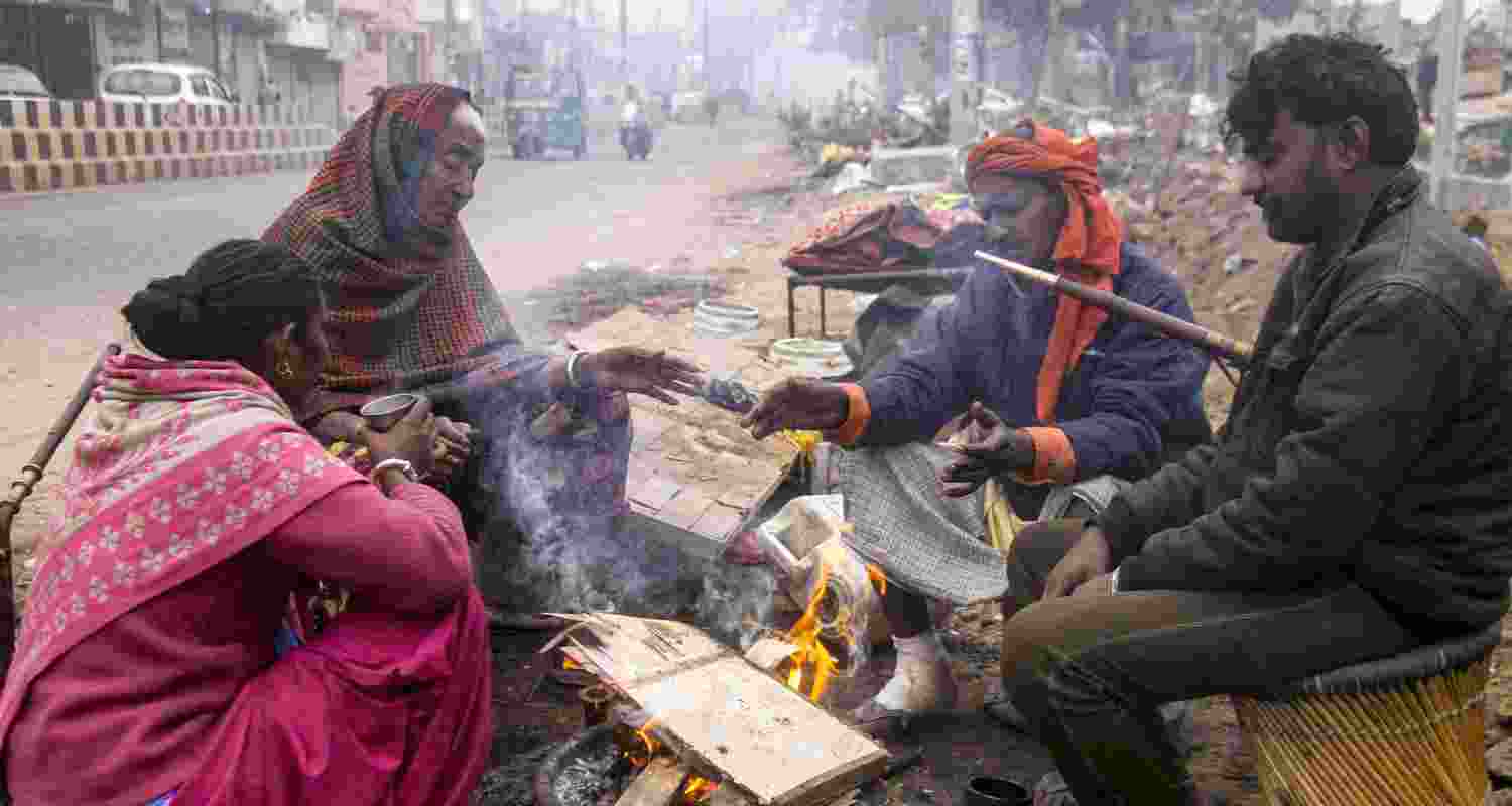 People sit around a bonfire on a cold winter morning, in Gurugram, Sunday. 