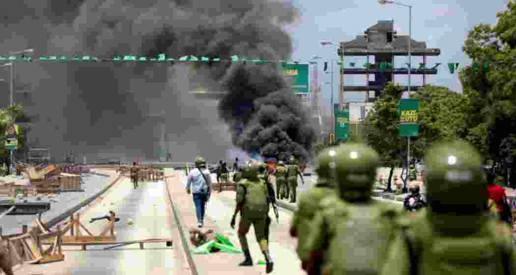 Police clash with protesters as smoke rises from burnt vehicles during unrest in Tanzania, where demonstrators took to the streets over political tensions, prompting a heavy security response.
