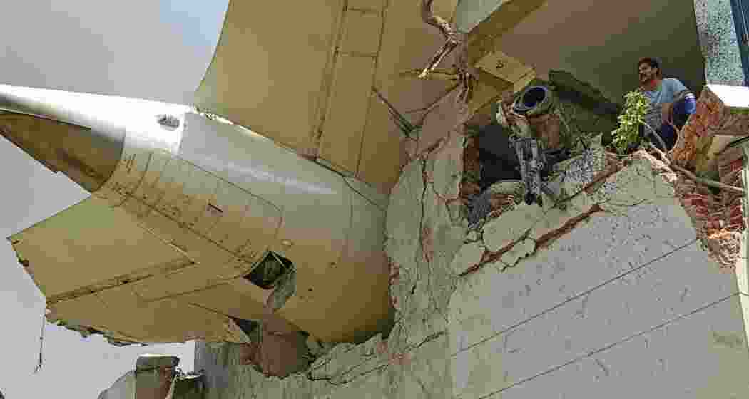 The tail section of the ill-fated Air India Dreamliner dangles precariously over the charred remains of the B. J. Medical College hostel building it struck on June 12, 2025, in Ahmedabad.