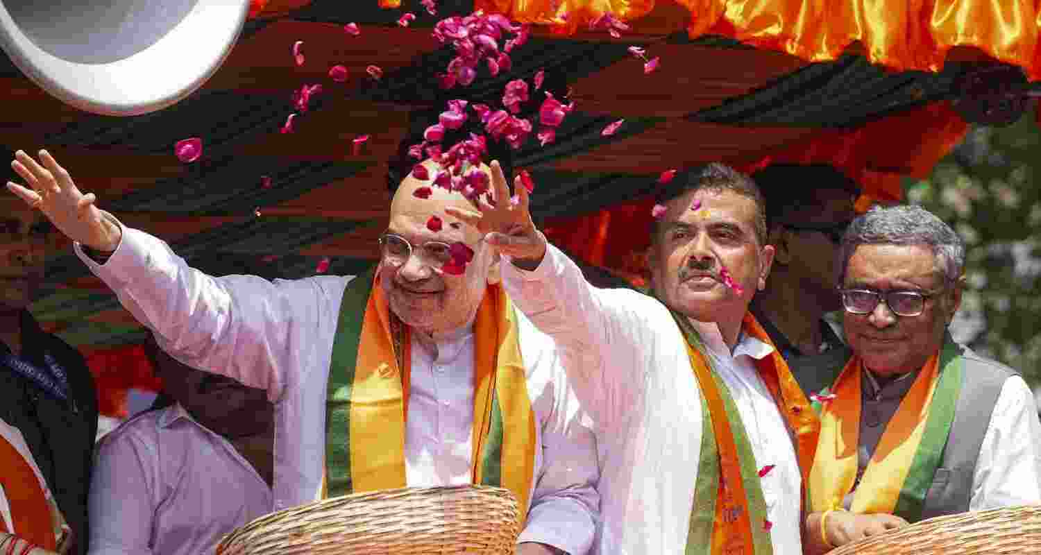 Union Home Minister Amit Shah, left, during a roadshow for filing of nomination papers by BJP candidates Suvendu Adhikari, centre, from Bhabanipur and Swapan Dasgupta from Rashbehari Assembly constituencies, in Kolkata, West Bengal. 