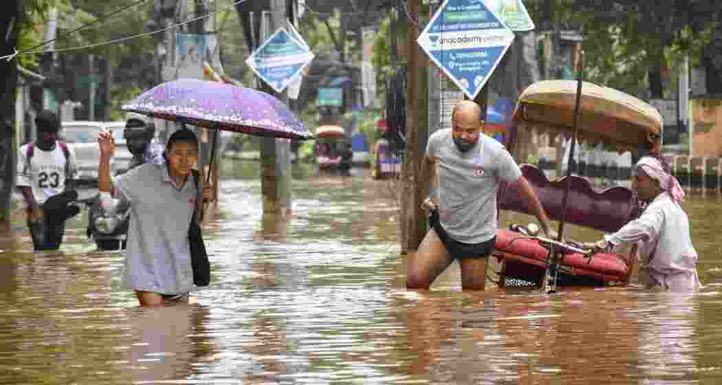 People wade through an area inundated with floodwater following heavy rainfall, at Anil Nagar area, in Guwahati, Assam, Thursday, June 5, 2025. Assam's flood situation remained grim on Thursday, with nearly seven lakh people affected in 21 districts and the water level of major rivers showing a rising trend, officials said. 