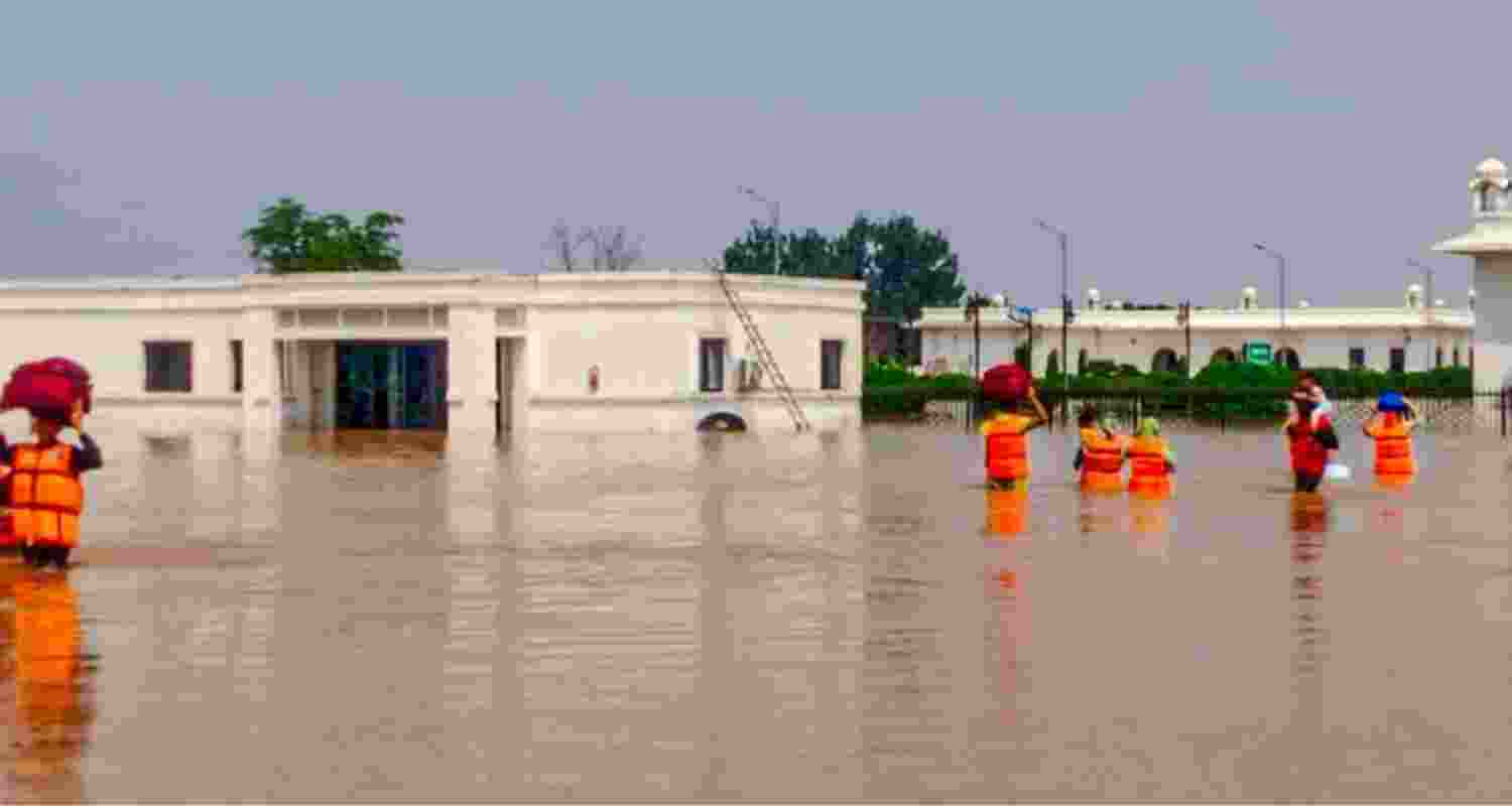 People making their way through a waterlogged Gurdwara Darbar Sahib complex in the Kartarpur Corridor in Pakistan.