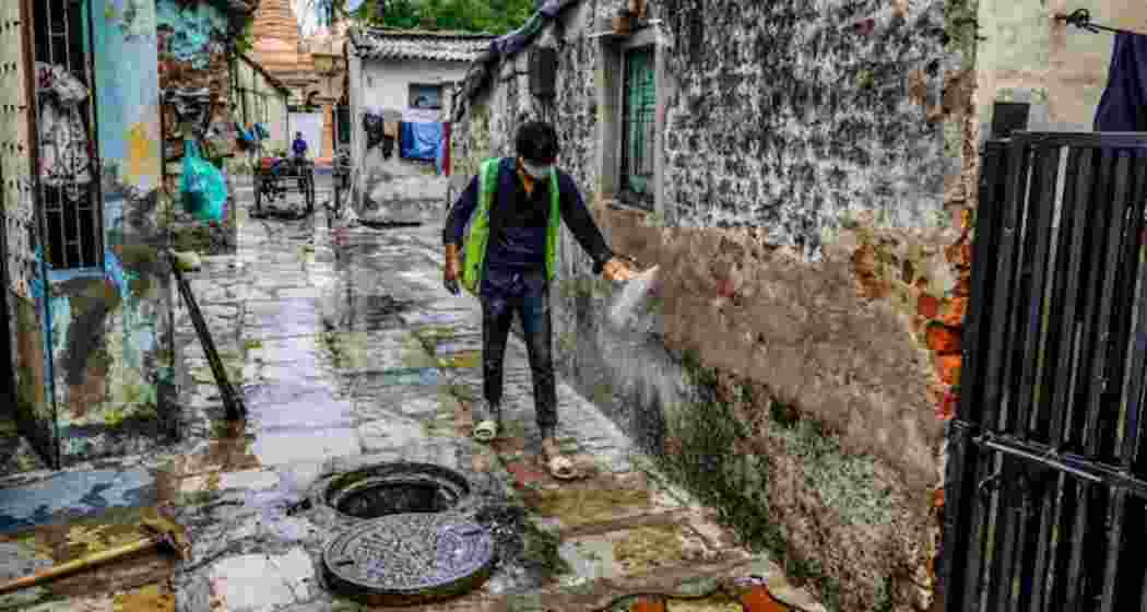 A municipal worker sprinkles gamaxine powder in a residential locality to curb the spread of Chandipura virus, in Ahmedabad.