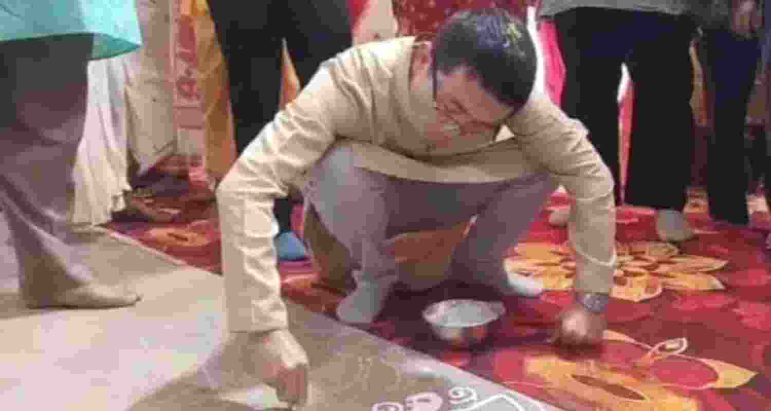 A Chinese guest offers alpana— handiwork on the floor where the Durga Puja is taking place.