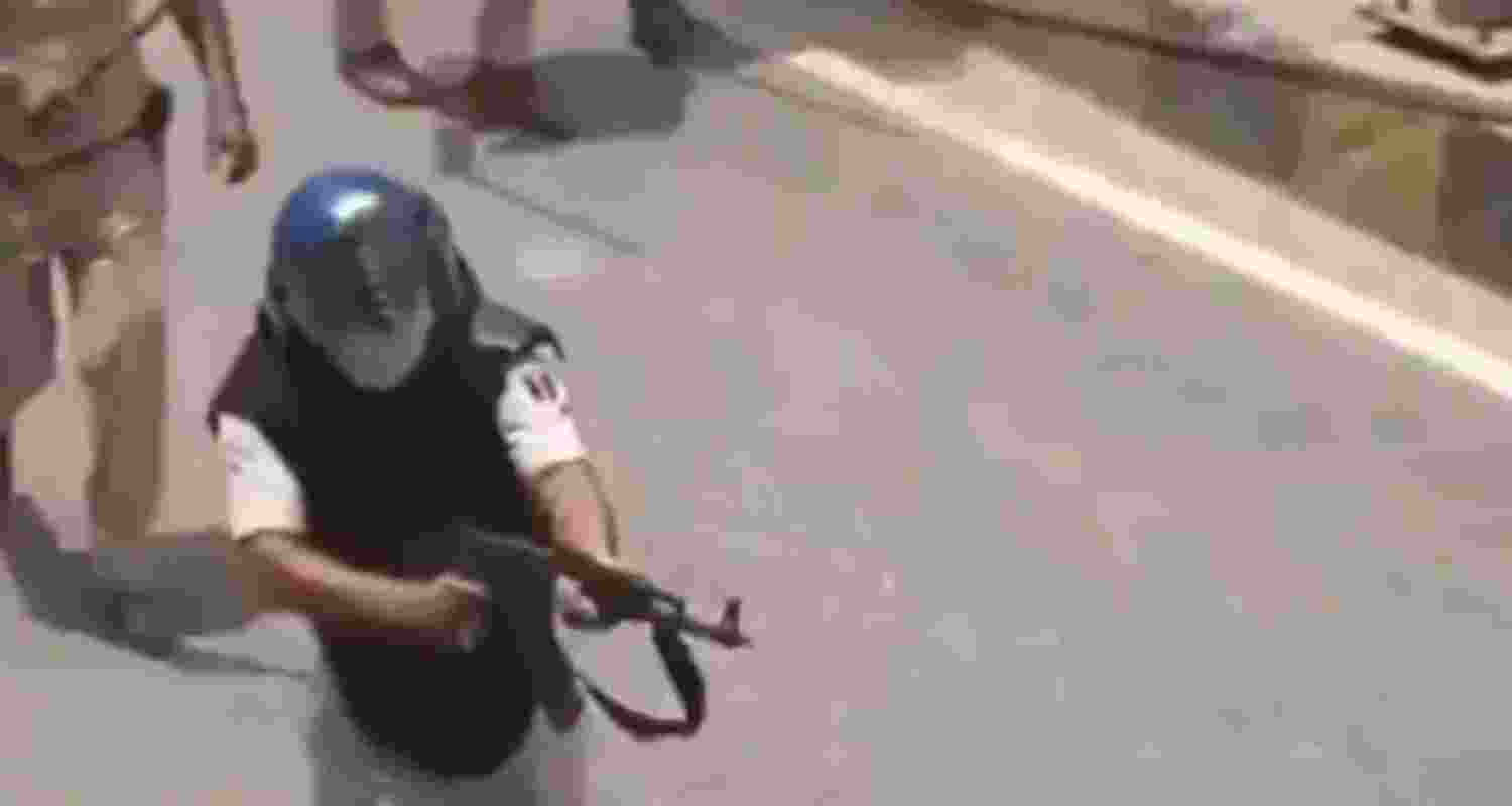 A screenshot from a viral video showing a police constable purportedly aiming an AK-47 rifle at student protesters. 
