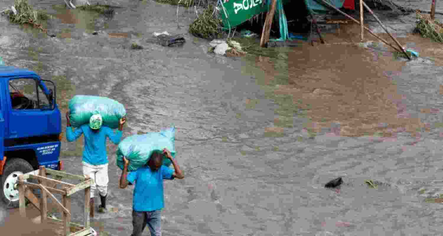 People carry sacks as they walk through floodwaters following heavy rainfall in the Ruai area of Nairobi, Kenya.