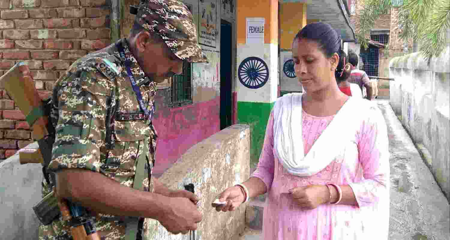 A security official checks credentials of a voter at a polling station during the re-election to the Falta assembly seat, in South 24 Parganas district, West Bengal, Thursday, May 21, 2026.