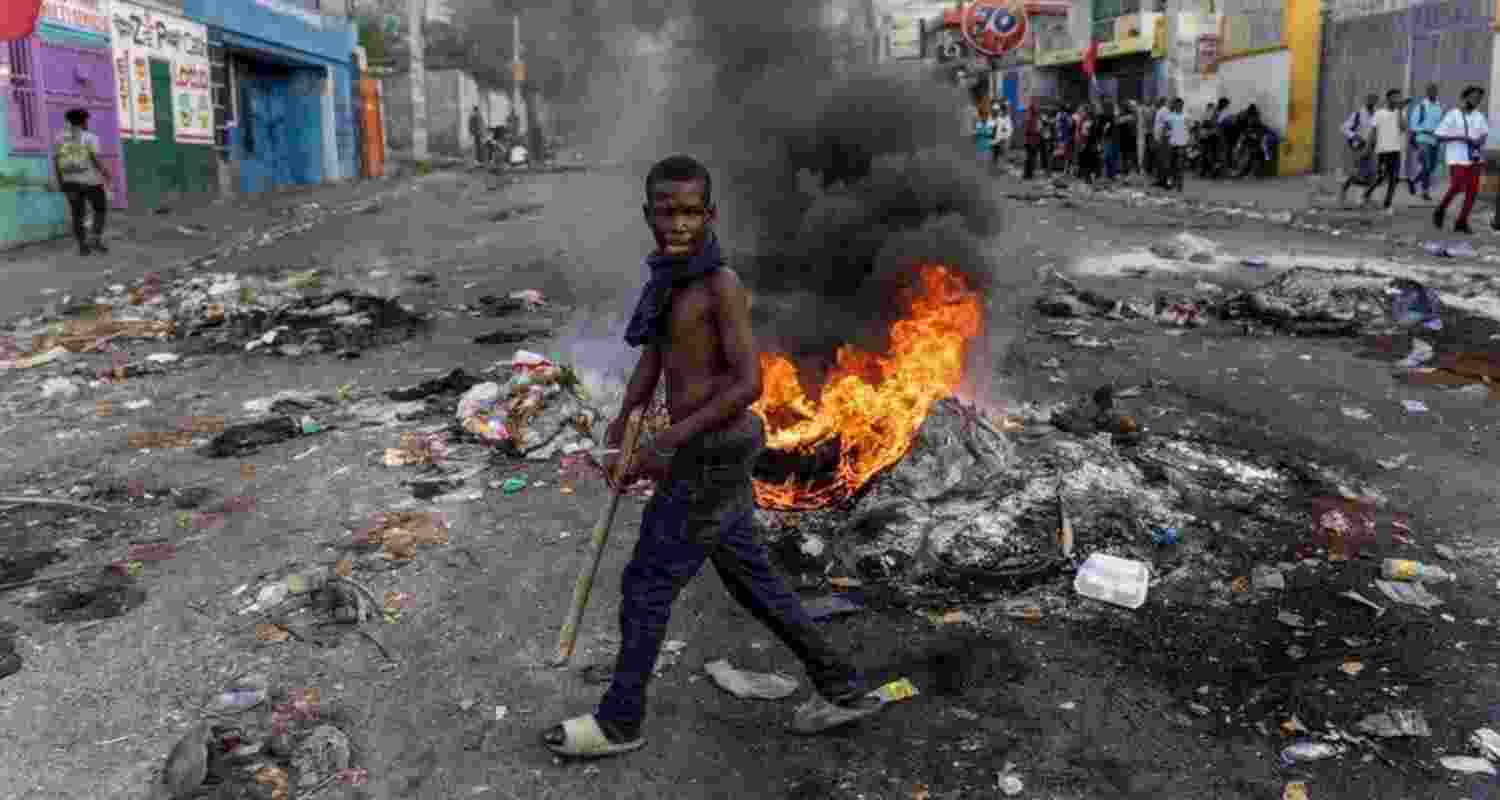A gang member is seen on a burning street in Haiti. Image via X.