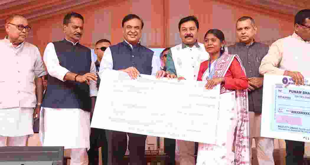 Assam CM Himanta Biswa Sarma distributes cheques to beneficiaries during a programme.
