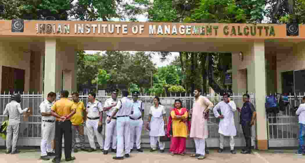 Police personnel stand guard as a crowd gathers outside the main entrance of IIM-Calcutta campus.