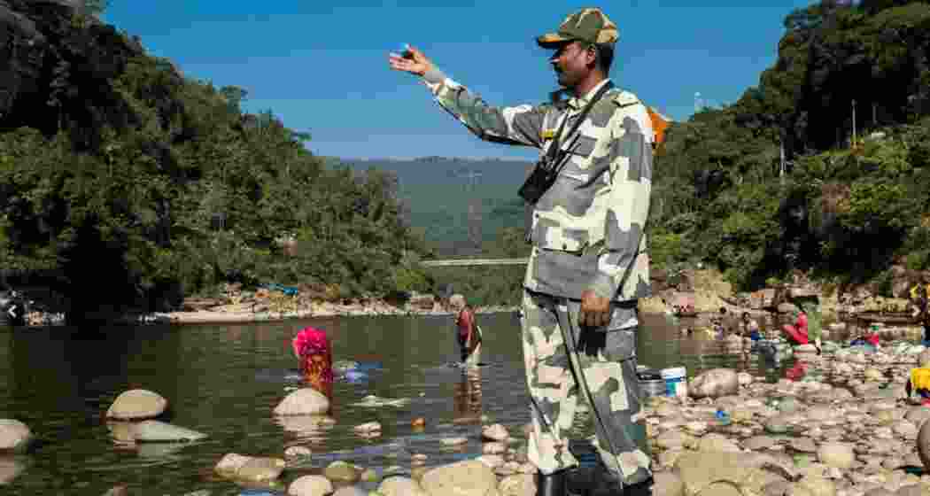 A BSF personnel points towards the India–Bangladesh border at Dawki in Meghalaya, highlighting the area where two Bangladeshi nationals were recently arrested for illegal entry into India.