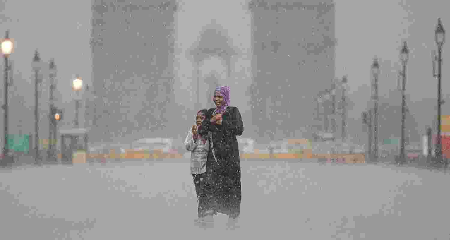 A woman with her child visits India Gate amid heavy rainfall in New Delhi, Tuesday.