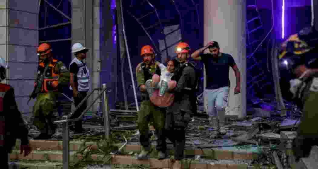 A rescue team carries a woman to safety after missile strikes hit central Israel, as emergency services scramble to respond to the escalating conflict between Iran and Israel.