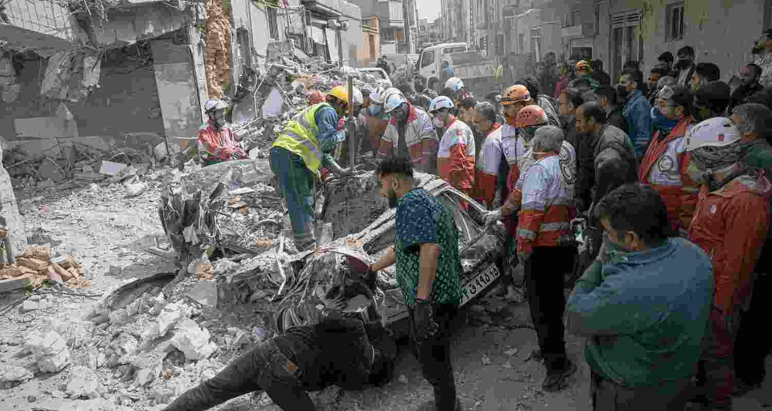 First responders inspect a destroyed car at the site of a residential building hit in an overnight strike during the U.S.-Israeli military campaign in Tabriz, East Azerbaijan Province, northwestern Iran, Tuesday, March 24, 2026.