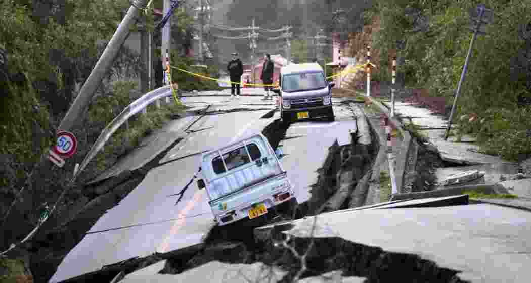 Locals watch over a cracked roadside where vehicles plunged halfway down after repeated tremors triggered landslides and ground shifts in Japan’s Tokara Islands. 
