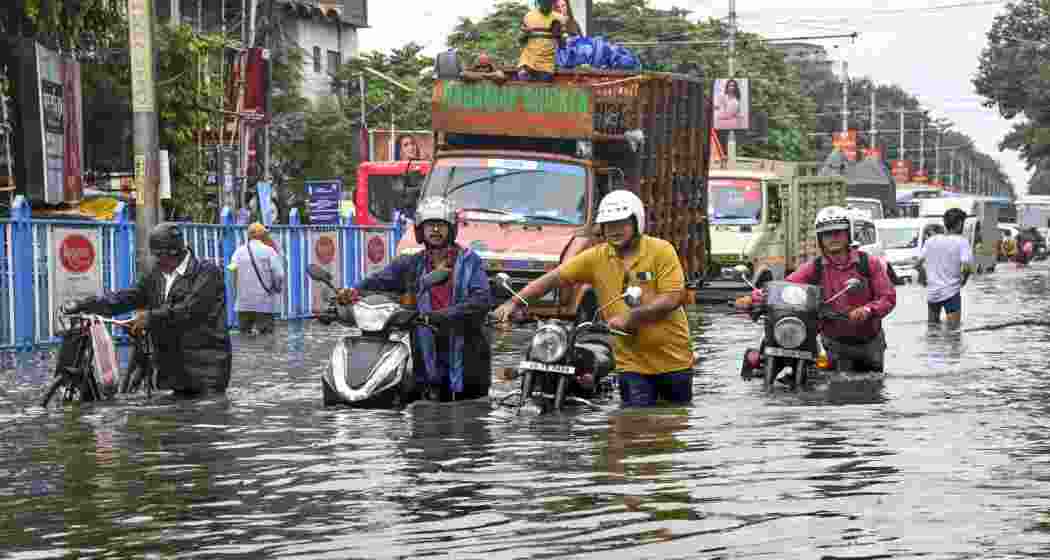 People make their way through a flooded road after heavy rainfall, in Kolkata on Tuesday.