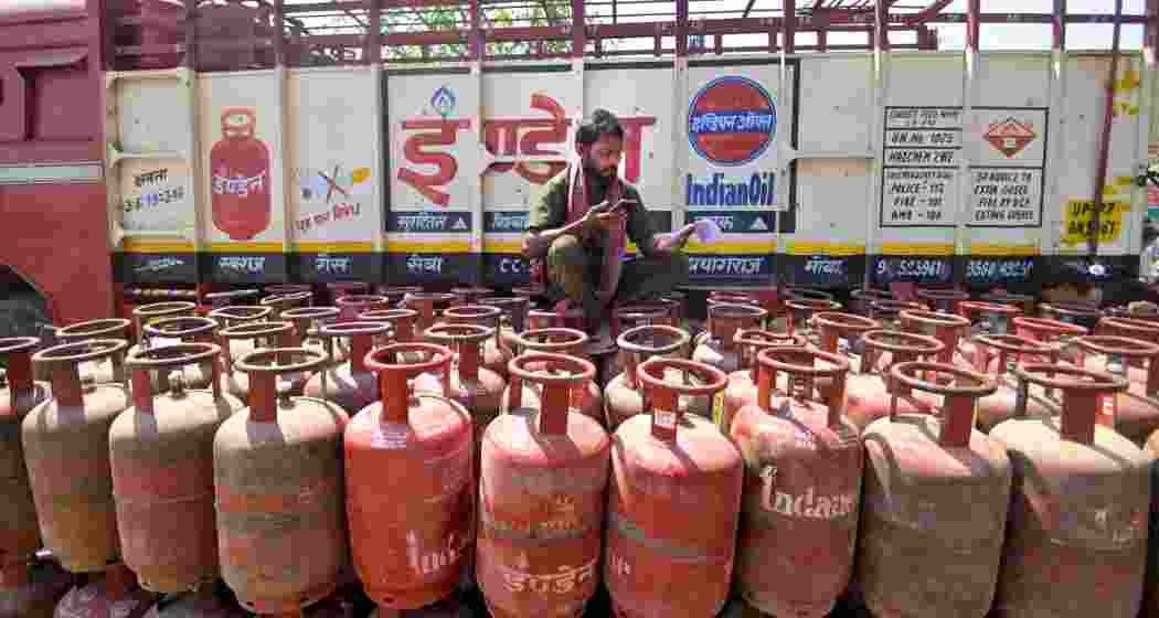 A worker sits on an empty LPG gas cylinder amid ongoing supply crisis. (PTI)