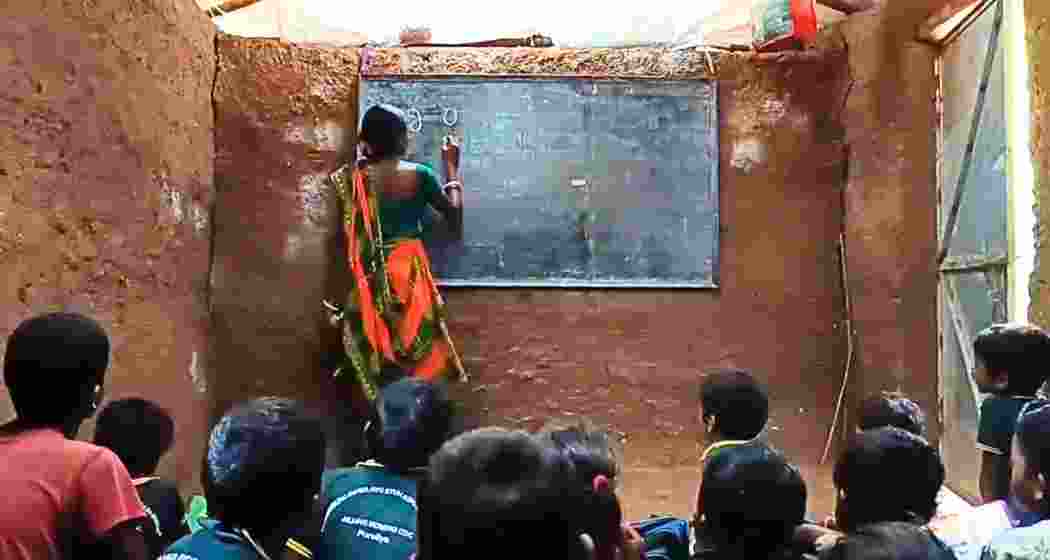 Malati Murmu conducts a class in Jiling Seren village as children learn seated on the mud floor.