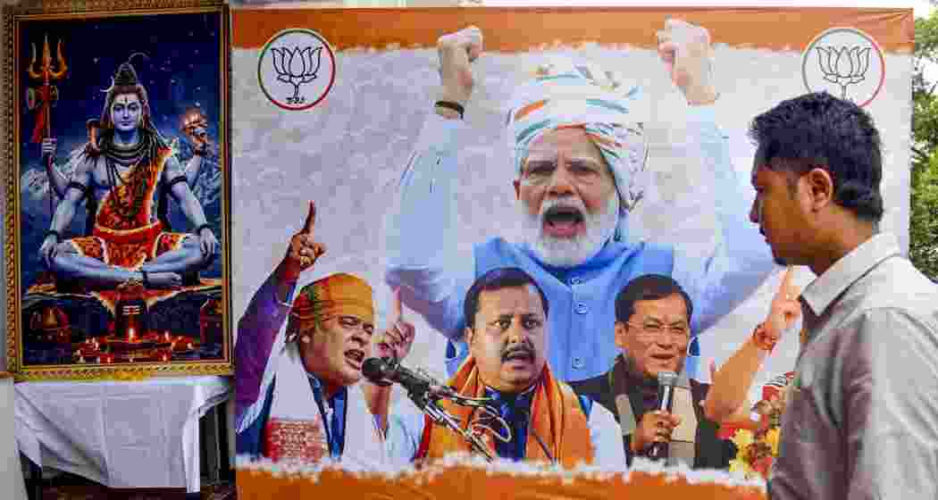 A man passes by a huge hoarding of BJP during the Assam Assembly elections result day, in Guwahati, on Monday.