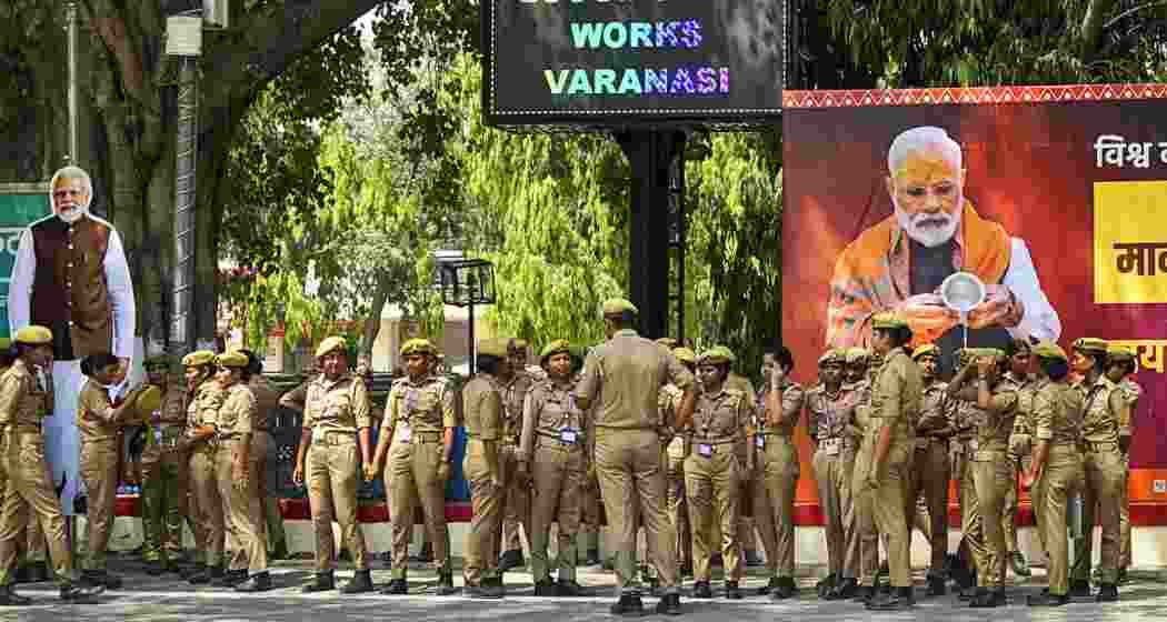 Police personnel stand guard near a hoarding of Prime Minister Narendra Modi ahead of his visit, in Varanasi, Uttar Pradesh, on Monday.