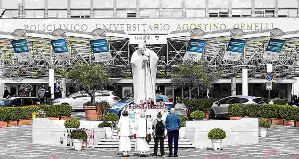 Faithful gather near Pope John Paul II statue outside Gemelli Hospital, where Pope Francis is undergoing treatment in Rome, Italy, on March 8, 2025.