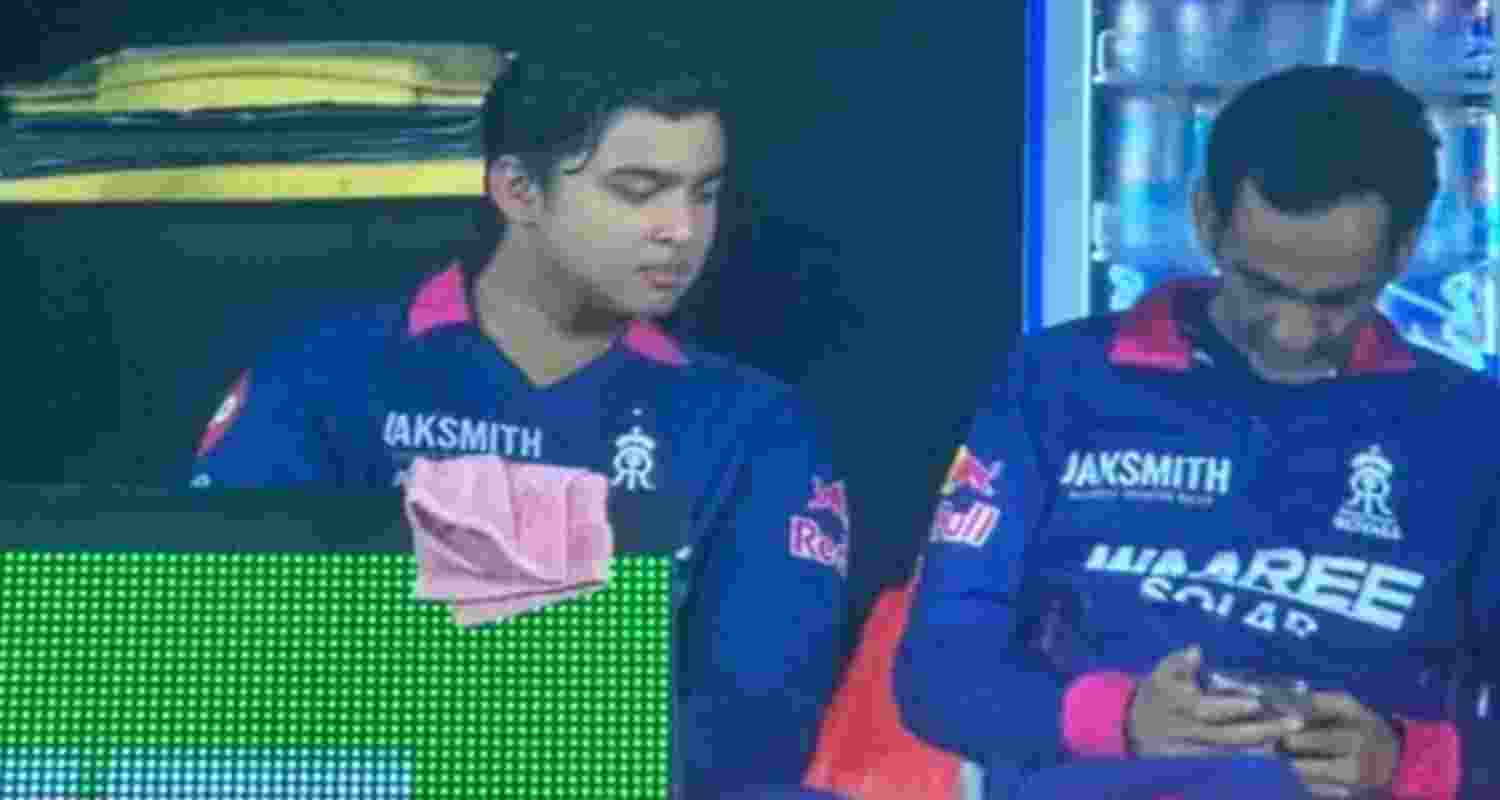 A file photo of Rajasthan Royals team manager Romi Bhinder using his phone in the dugout as opener Vaibhav Sooryavanshi looks on.