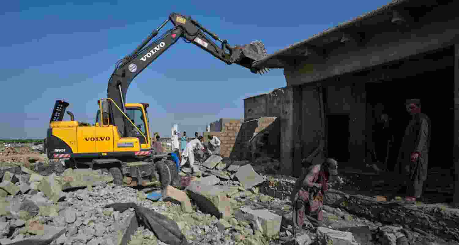 A hydraulic shovel demolish a structure during an operation against illegal settlement of Afghan refugees conducted by local government, on the outskirts of Karachi, Pakistan, Wednesday.