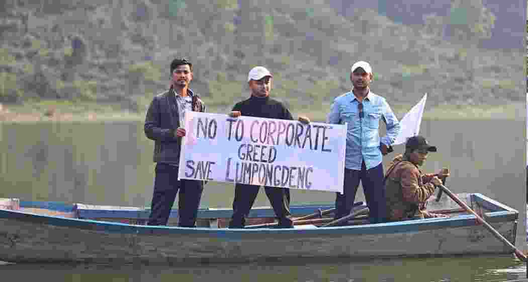 Protesters hold placards on a boat at Umiam Lake, opposing the proposed resort project and inclusion of Lumpongdeng Island.