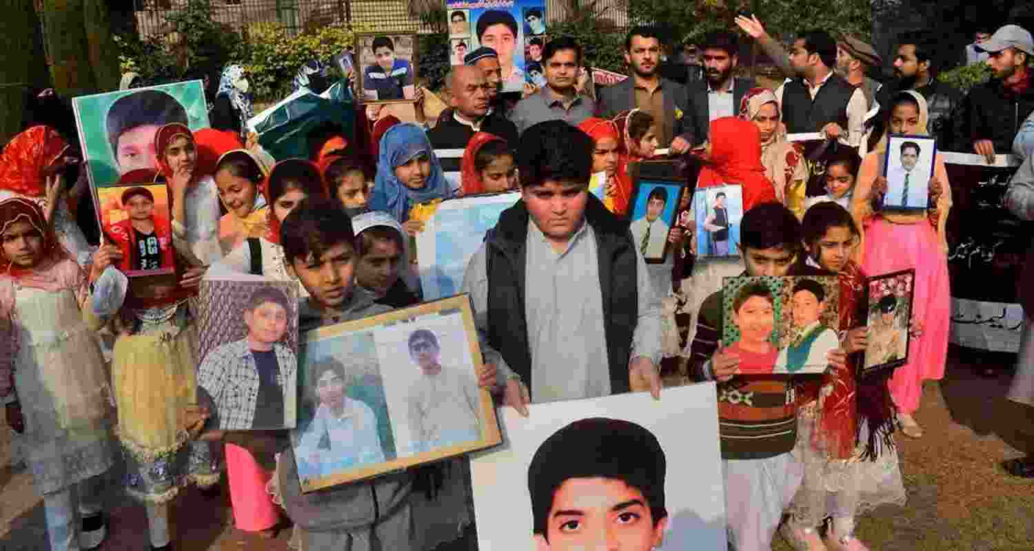 Families in Pakistan carry photos of their relatives killed in a 2014 attack by TTP fighters on Peshawar’s army public school. 