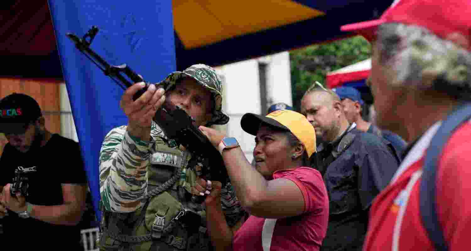 A member of the Bolivarian National Militia shows a woman how to operate a weapon during military exercises in Caracas.