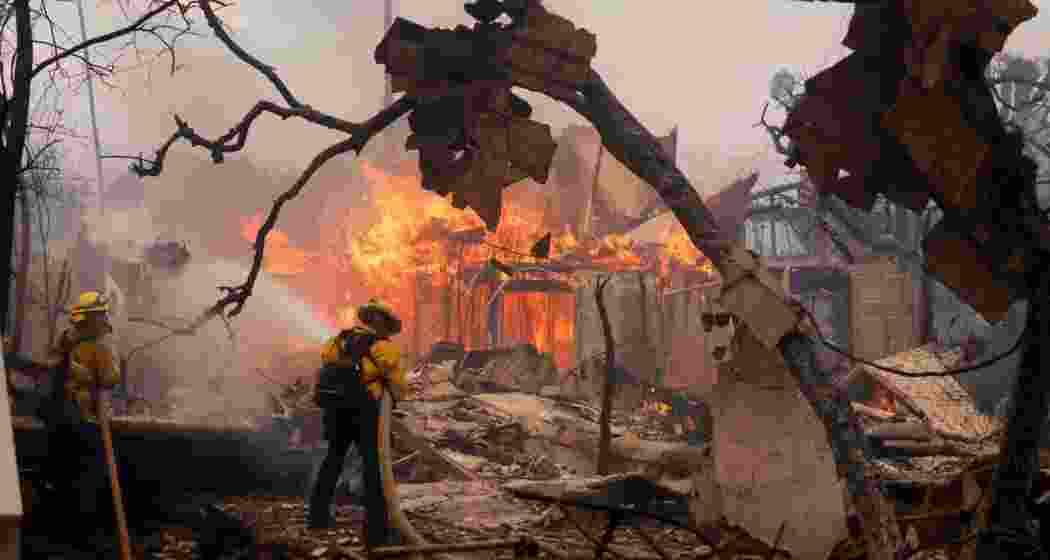 Firefighters battle the Palisades Fire as it burns a structure in the Pacific Palisades neighborhood of Los Angeles. 