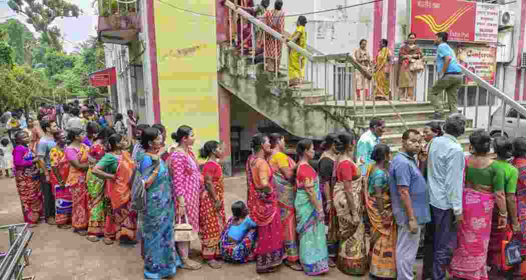 People stand in queue outside a Post Office to complete the verification process for the ‘Annapurna Yojana‘ financial assistance scheme for women, in Balurghat, West Bengal. People stand in queue outside a Post Office to complete the verification process for the ‘Annapurna Yojana‘ financial assistance scheme for women, in Balurghat, West Bengal.
