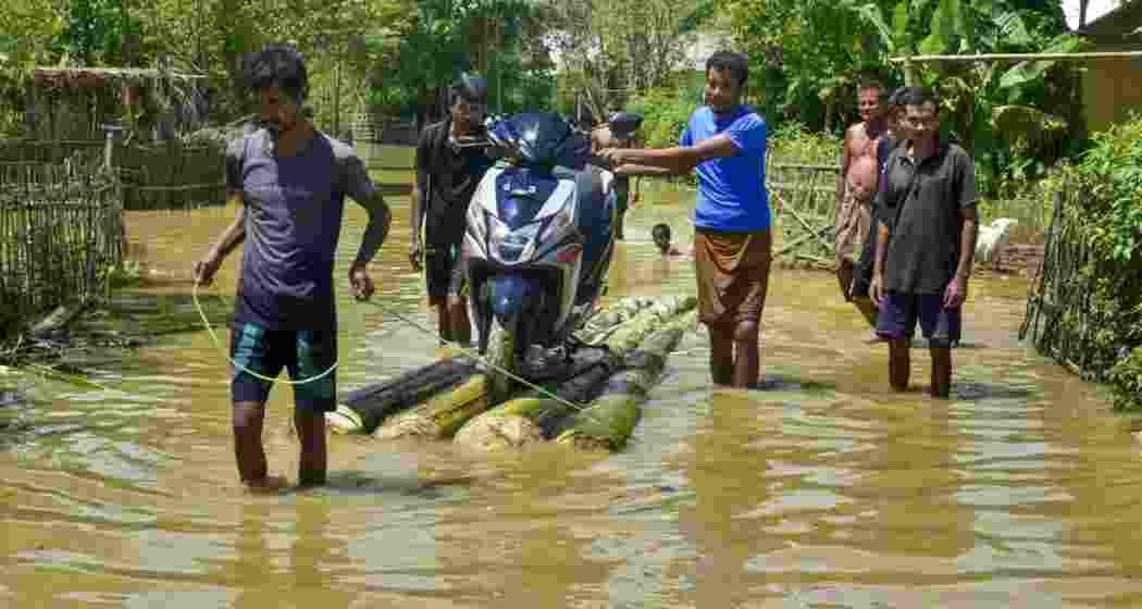 People transport a motorcycle through a flood-affected area on a makeshift raft after heavy rainfall in Golaghat, Assam. People transport a motorcycle through a flood-affected area on a makeshift raft after heavy rainfall in Golaghat, Assam.