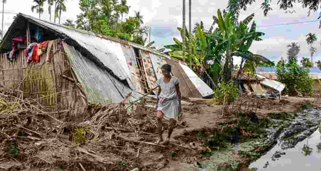 A woman walks past a damaged house affected by the flood in Assam. A woman walks past a damaged house affected by the flood in Assam.