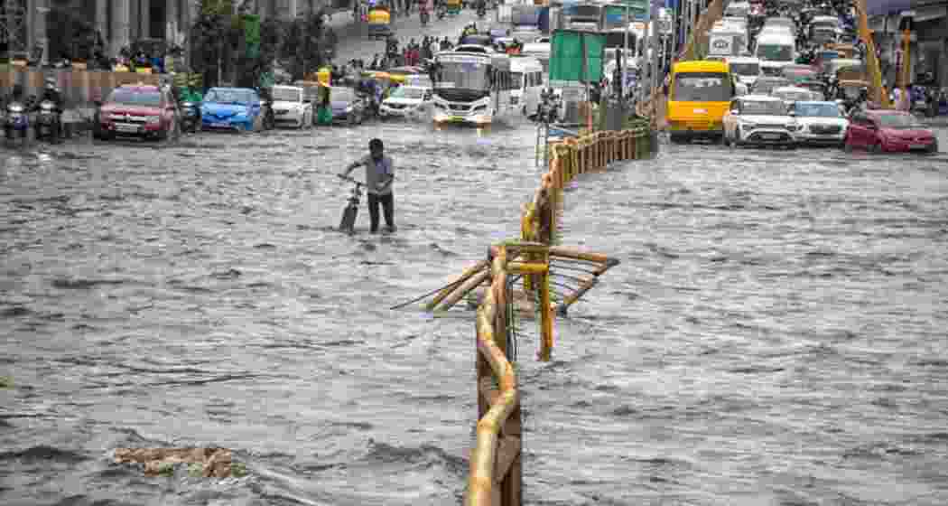 Commuters wade through a waterlogged road after heavy rains, in Bengaluru, Tuesday. Commuters wade through a waterlogged road after heavy rains, in Bengaluru, Tuesday.