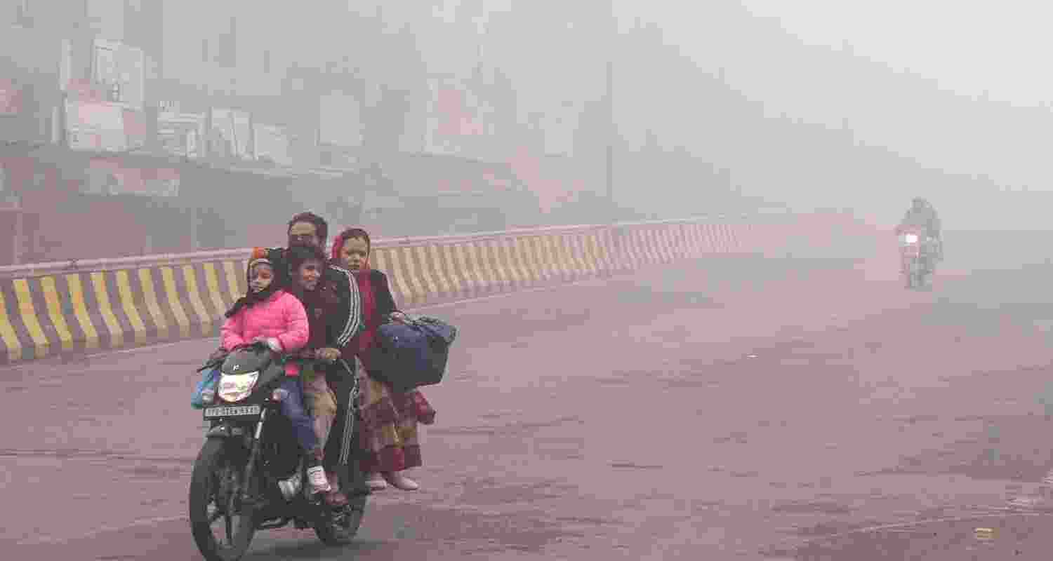 A family rides a motorcycle amid dense fog during a cold winter morning, in Amritsar. A family rides a motorcycle amid dense fog during a cold winter morning, in Amritsar.