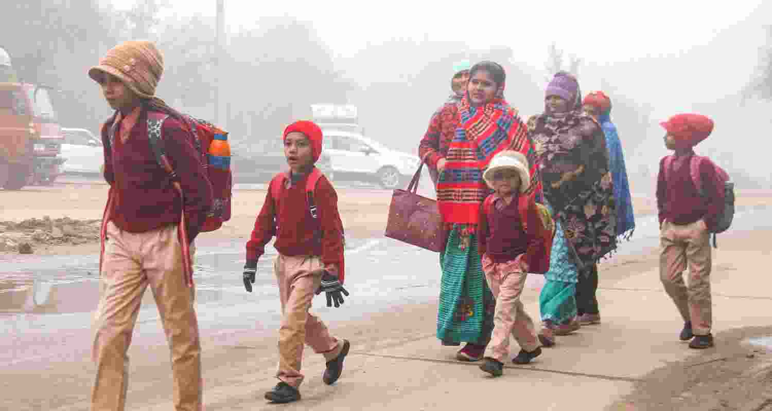 Students wearing warm clothes along with their guardians walk to their school during a foggy and cold winter morning, in Gurugram. Students wearing warm clothes along with their guardians walk to their school during a foggy and cold winter morning, in Gurugram.