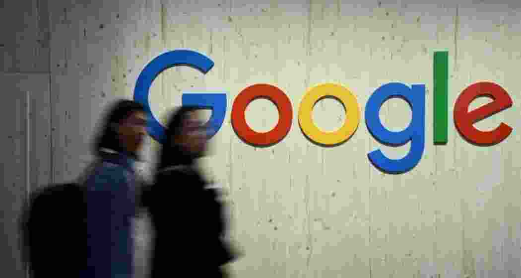 People walk along a Google logo. People walk along a Google logo.