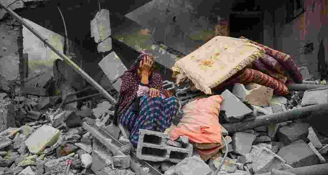A Palestinian woman sits on the rubble of her house, destroyed in an Israeli strike, in the Nuseirat refugee camp in central Gaza. A Palestinian woman sits on the rubble of her house, destroyed in an Israeli strike, in the Nuseirat refugee camp in central Gaza.