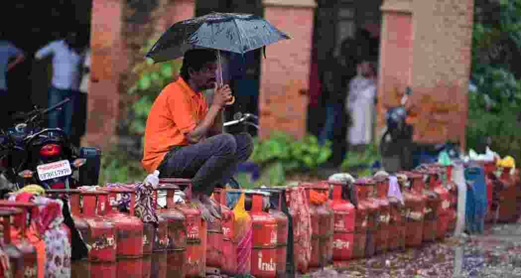 A man sits over an LPG cylinder amid rainfall, during an ongoing supply crisis, in Prayagraj, on Friday. A man sits over an LPG cylinder amid rainfall, during an ongoing supply crisis, in Prayagraj, on Friday.