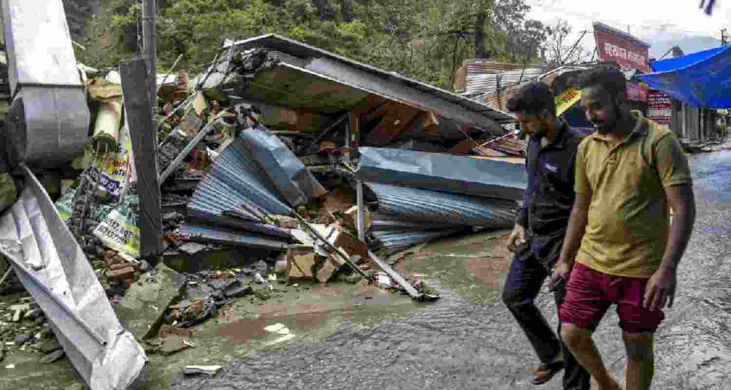 Men walk past flood-damaged structures after heavy rains triggered a cloudburst and landslides, at Sahastradhara, in Dehradun. Men walk past flood-damaged structures after heavy rains triggered a cloudburst and landslides, at Sahastradhara, in Dehradun.