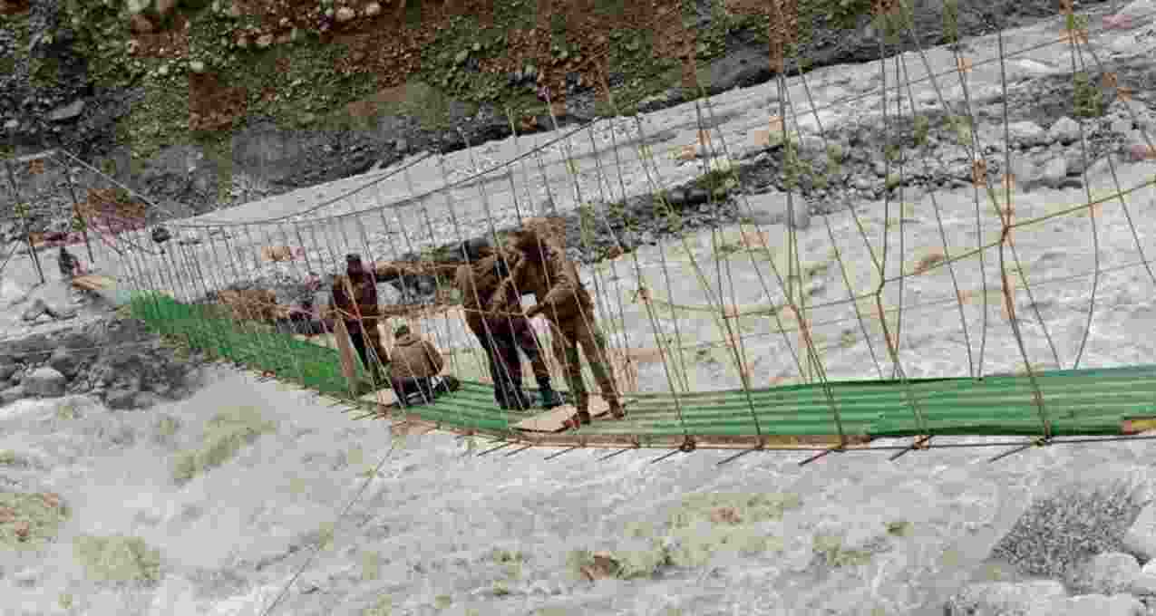 The 150-foot suspension bridge, being constructed by engineers of Indian Army, being given final touches under a fast flowing river. The 150-foot suspension bridge, being constructed by engineers of Indian Army, being given final touches under a fast flowing river.