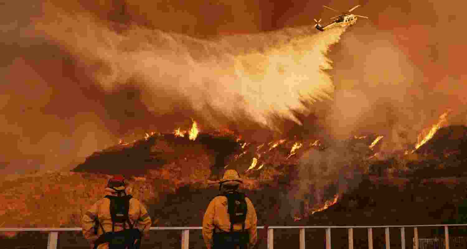 Firefighters watch as water is dropped on the Palisades Fire in Mandeville Canyon on Monday. Firefighters watch as water is dropped on the Palisades Fire in Mandeville Canyon on Monday.
