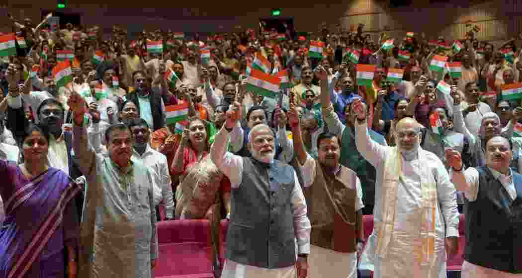 Prime Minister Narendra Modi waving towards NDA MPs holding the national flag after they greeted him in the Parliament Library ahead of the weekly parliamentary party meeting. Prime Minister Narendra Modi waving towards NDA MPs holding the national flag after they greeted him in the Parliament Library ahead of the weekly parliamentary party meeting.